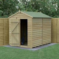 Wooden windowless apex shed, 8'x6', with overlap cladding and green roof, set in a garden with wooden fencing.