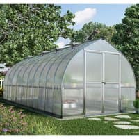 Silver Palram Canopia Bella greenhouse with arched roof, clear panels, and double doors, set in a garden.
