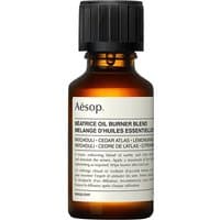 Amber glass bottle with black cap, labeled "Aesop Beatrice Oil Burner Blend Woody Essential Oil."