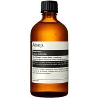 Amber glass bottle of Aesop Breathless 100 ml moisturizing body oil with white label and black text.