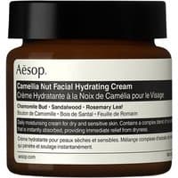 Brown jar of Aesop Camellia Nut Facial Hydrating Cream with black lid and white label detailing product information.