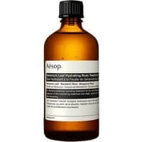 Amber glass bottle of Aesop Geranium Leaf Hydrating Body Treatment with white label and black cap, 100 ml.