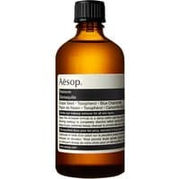 Amber glass bottle with black cap, labeled "Aesop Remove 60 ml Cleansing Eye Oil For All Skin Types" in black and white text.