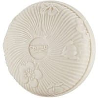 Round white soap with embossed floral design and "CREED" logo in the center.