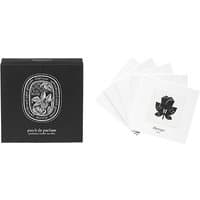 Black Diptyque box with floral design, next to white perfumed stickers featuring a black rose illustration.