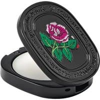 Black oval compact with embossed rose design, containing Diptyque Eau Rose floral solid perfume.
