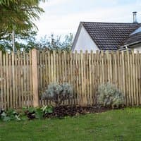 Forest pressure-treated picket fence panel, 6' x 3', vertical slats, natural wood finish, garden setting.