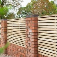 Pressure-treated double slatted fence panel with horizontal wooden slats, framed by red brick pillars.