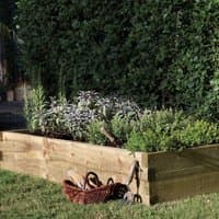 Rectangular wooden raised bed planter with herbs, natural finish, 6'x3', set on grass with garden tools nearby.