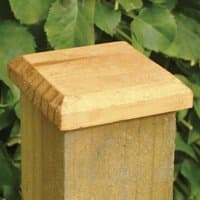 Wooden Forest Fence Post Cap 10 x 10cm with beveled edges, natural finish, atop a square post against green foliage.