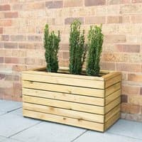 Wooden garden planter with horizontal slats, rectangular shape, housing three tall green plants against a brick wall.
