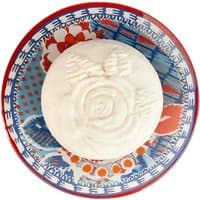 White soap with embossed rose design on colorful patterned dish.