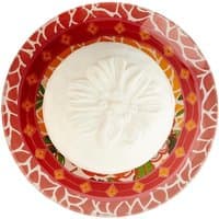White floral-embossed soap on a vibrant red and orange patterned ceramic soap dish.