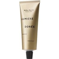 Gold tube of Miller Harris Lumiere Doree hand cream, black cap, elegant black text.