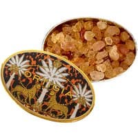 Ortigia Ambra Nera scented crystals in an oval tin with palm tree and leopard design, amber-colored stones inside.