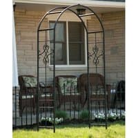 Black metal garden arch with quatrefoil design, curved top, and lattice sides, standing in front of a house.