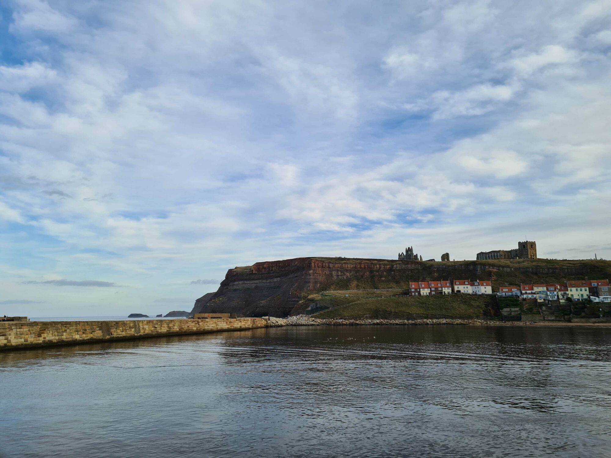 Image name whitby harbour and and cliffs calm sea copyright yorkshire com international ltd the 3 image from the post Looking Forward to Spring Bank Holiday in Yorkshire: Top Places to Visit and Where to Stay in Yorkshire.com.