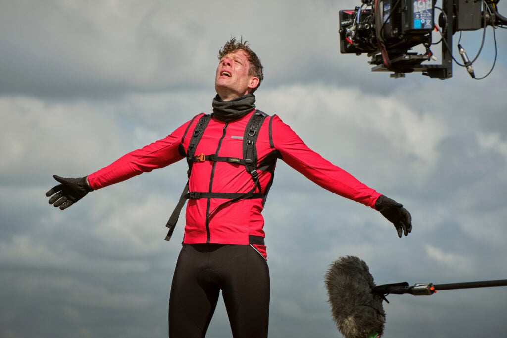 James Norton as Tommy Lee Royce in Happy Valley 3, filming behind the scenes in cycling outfit above Warley Moor reservoir with bike