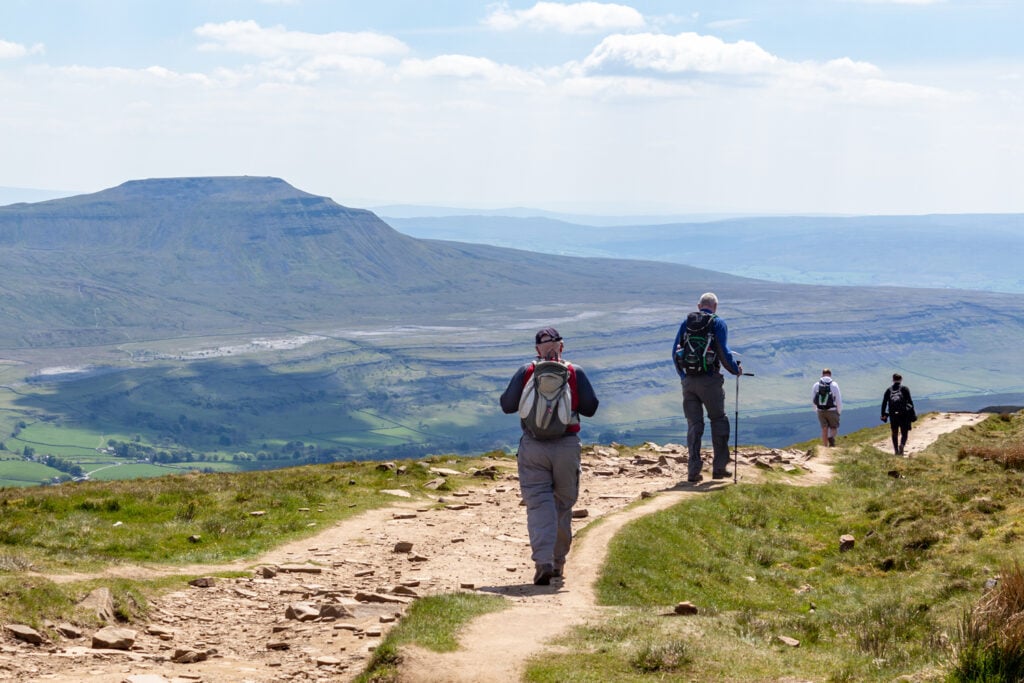 Image name walkers descending whernside view of ingleborough sunny yorkshire the 5 image from the post Easter holidays in Yorkshire in Yorkshire.com.