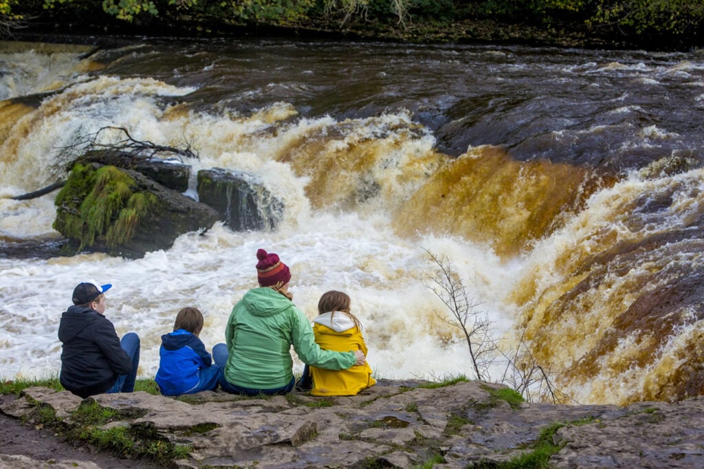 A family sitting in front of Aysgarth Falls